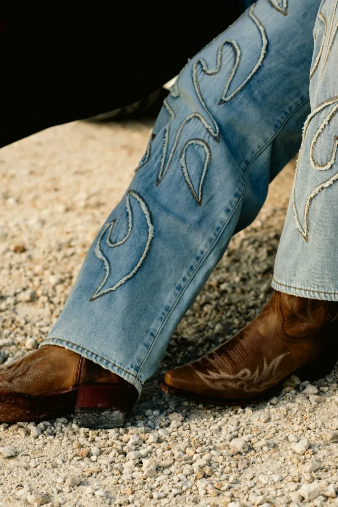 Embroidered boot-cut jeans stacked over tooled western boots