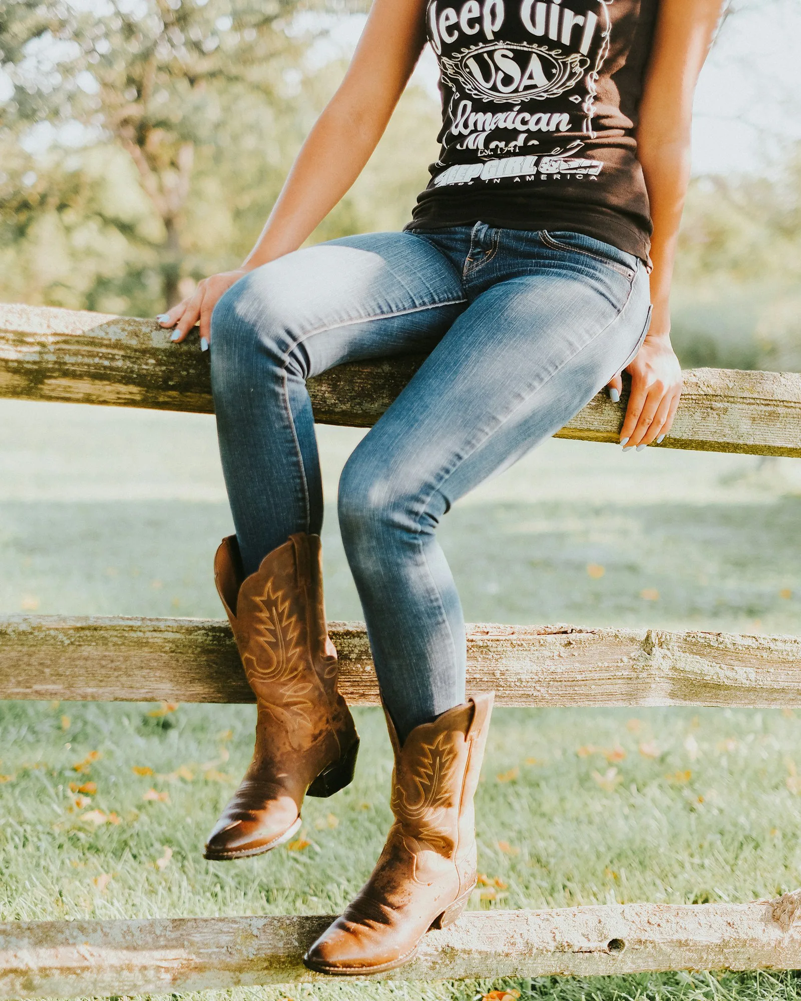 Boot-cut jeans and western boots resting on a ranch fence