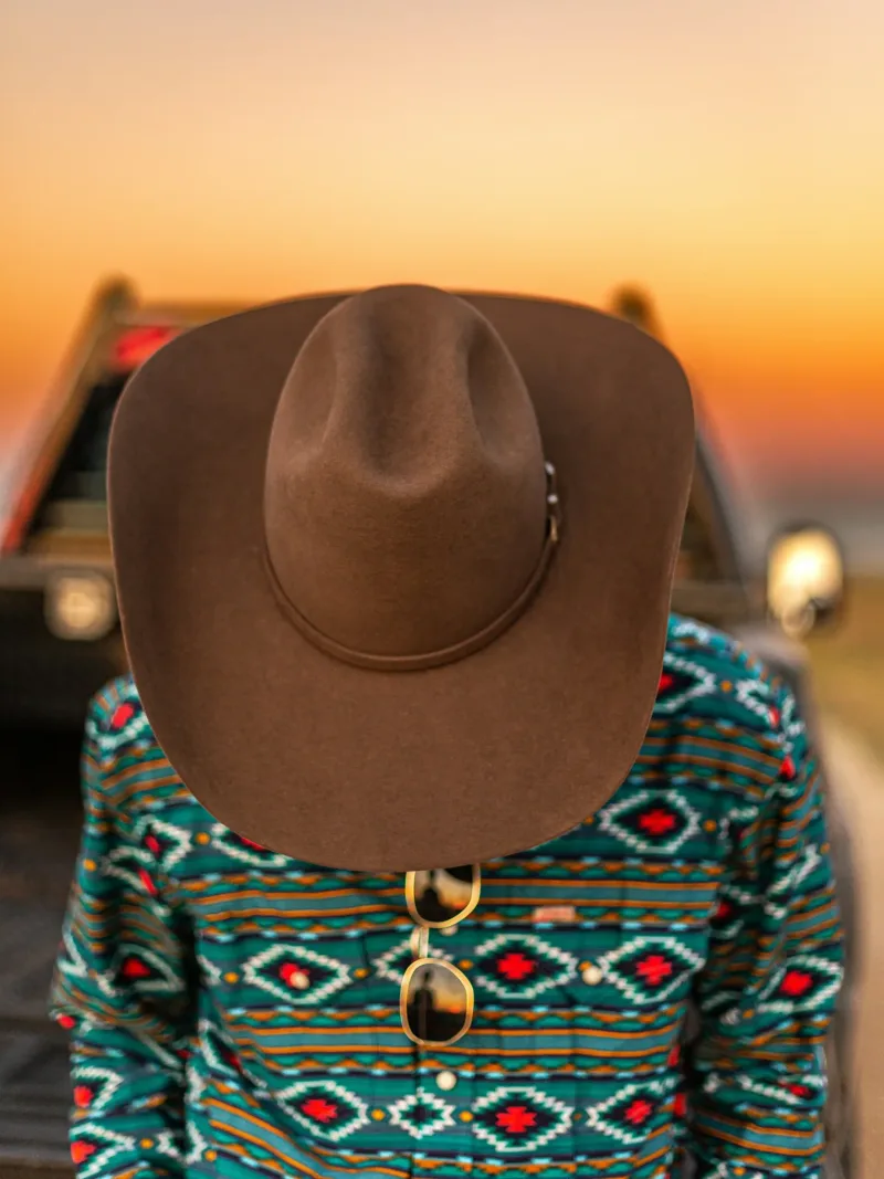 Aztec pattern fleece and felt hat facing a desert sunset